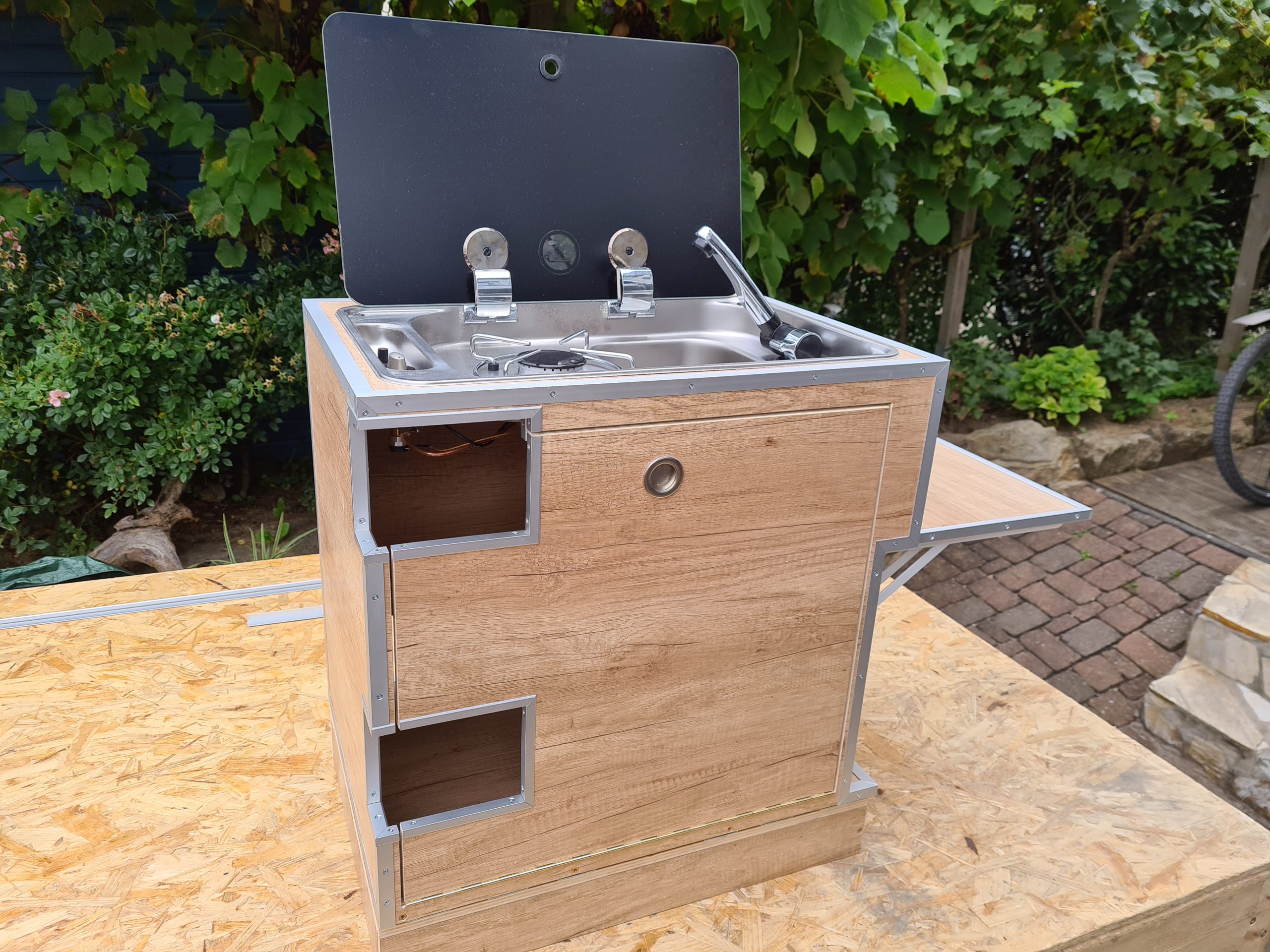 Praktisch organisierte Campingküche im Aluminiumkoffer – maßgefertigte Holzeinsätze für Gaszubehör, Kochgeschirr, Besteck und Gläser sorgen für Ordnung, schnellen Zugriff und klapperfreien Transport auf Reisen